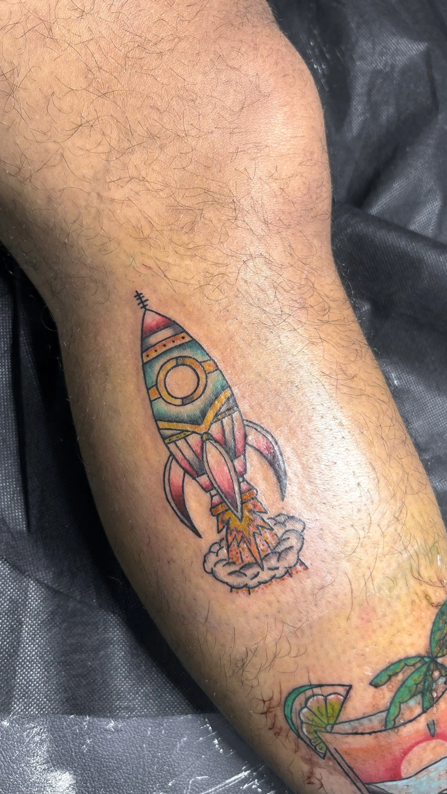 Tattoo motif roket dan ilustrasi berwarna di kaki · Meigu Tattoo