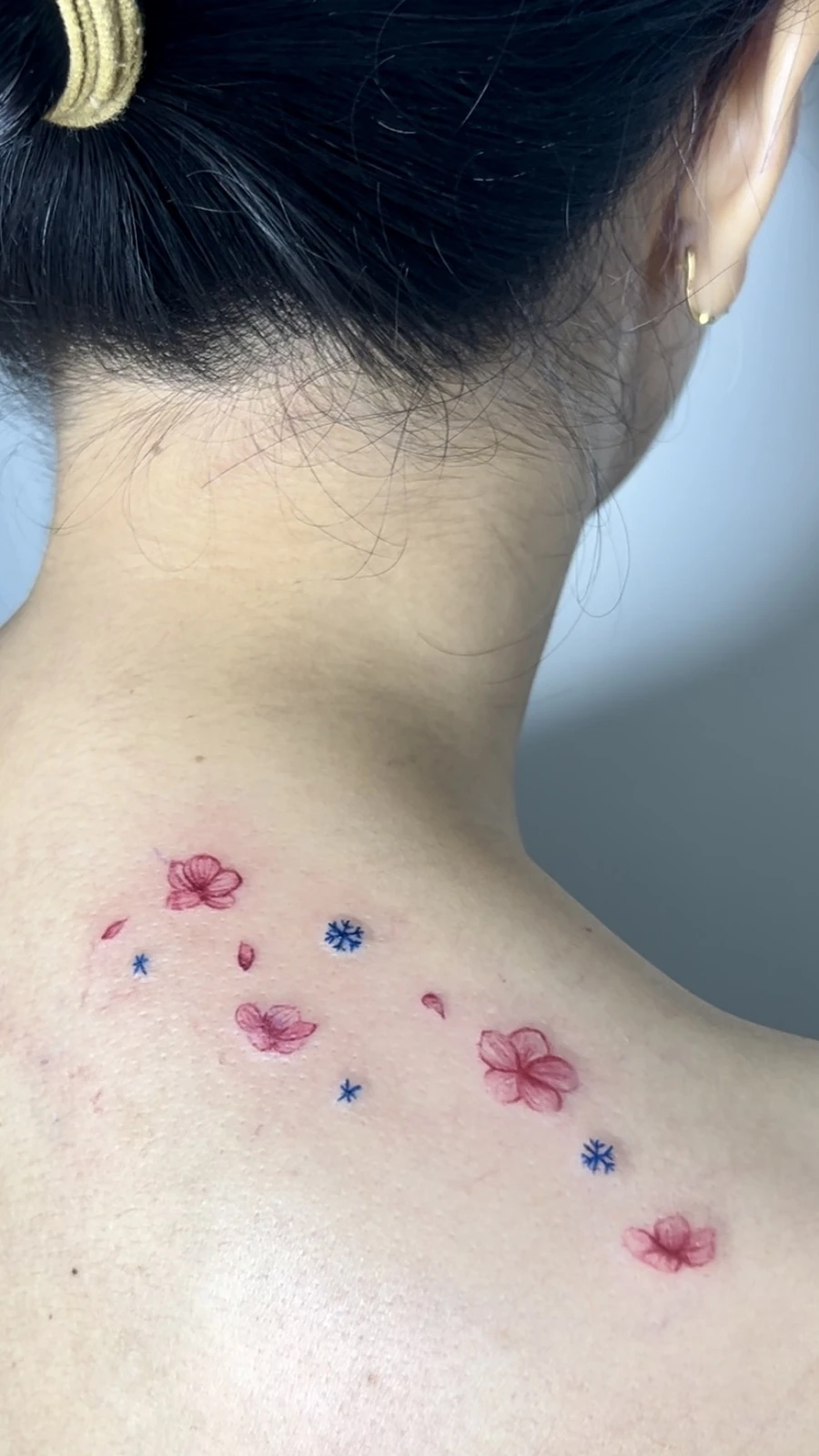 Tattoo bunga kecil berwarna di tengkuk · Meigu Tattoo