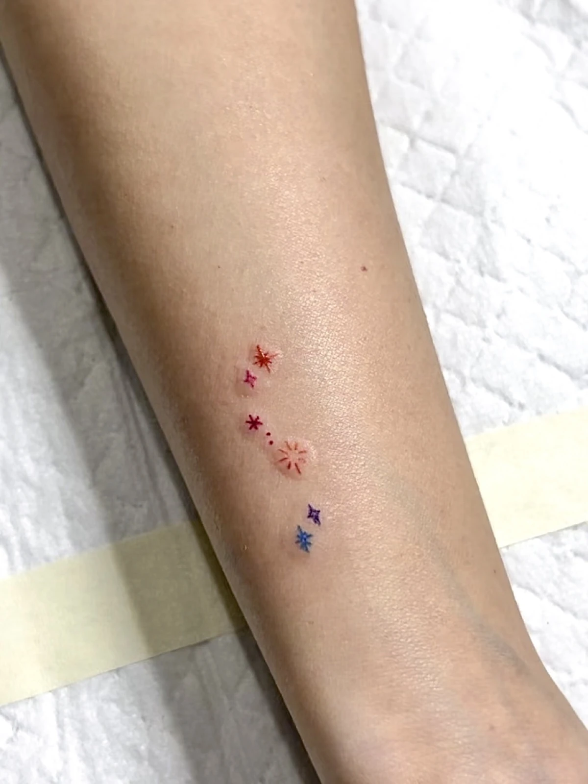 Tattoo motif kecil merah dan ungu di lengan · Meigu Tattoo